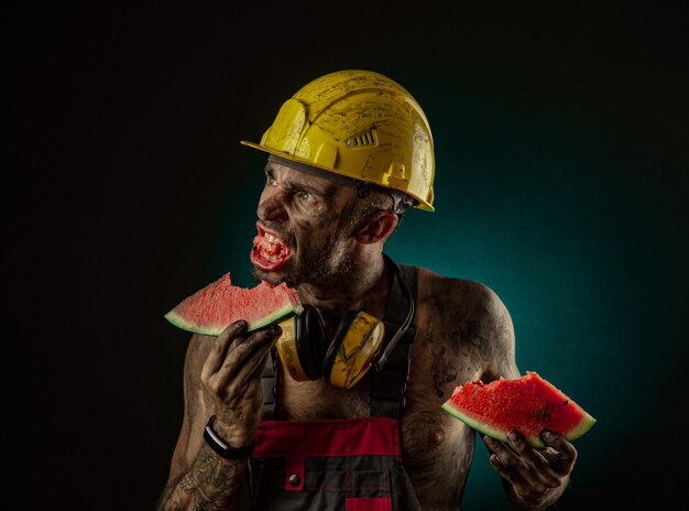 Il ritratto di un minatore sorridente felice che mangia anguria per pranzo