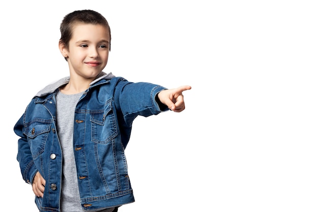 Il ritratto di un ragazzo sorridente in una giacca di jeans indica la direzione e si rallegra dei suoi successi