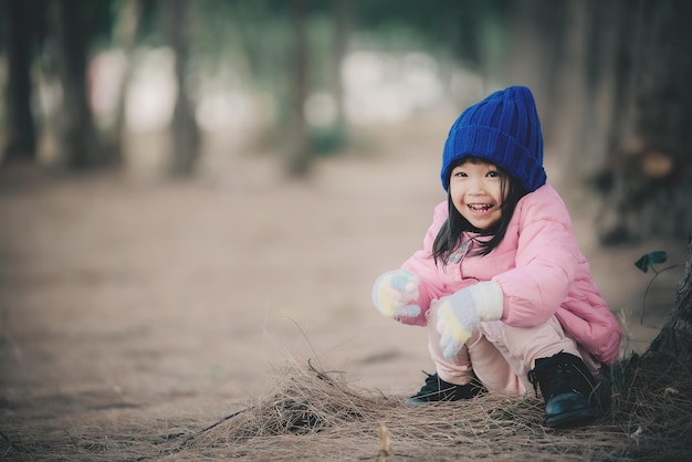 Il ritratto di una bambina asiatica carina indossa abiti invernali nella foresta del parco La gente della Thailandia posa per scattare una foto Tempo felice