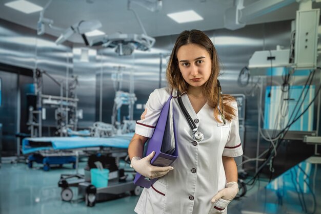 Il ritratto di una giovane dottoressa o assistente medico indossa un'uniforme bianca con uno stetoscopio Lavora in una moderna sala operatoria