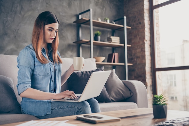 Il ritratto di una ragazza abbastanza alla moda usa il laptop a casa