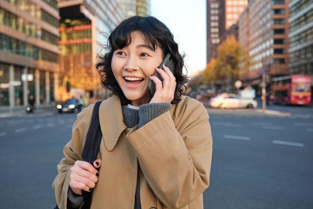 Il ritratto di una ragazza coreana felice parla al cellulare sembra sorpreso e felice riceve un grea positivo
