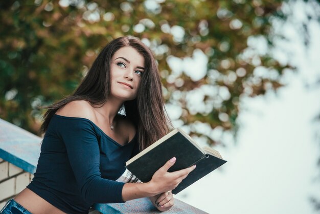 Il ritratto di una studentessa di college sorridente sta tenendo il libro