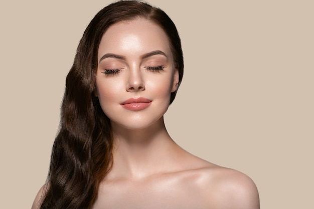 Il ritratto femminile di bellezza della donna della pelle dei bei capelli naturale compone i capelli lunghi. Colore di sfondo marrone