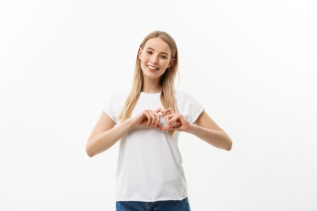 Il ritratto isolato di bella donna caucasica fa il simbolo del cuore a mano.