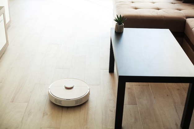 Il robot aspirapolvere funziona sul pavimento di legno in un soggiorno