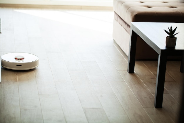 Il robot aspirapolvere Smart House funziona sul pavimento di legno in un soggiorno