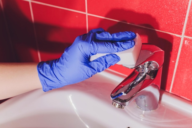 Il rubinetto dell'acqua in dettaglio con calcare vicino bagno sporco rubinetto calcificato guanti per il lavaggio spugna
