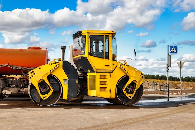 Il rullo vibrante posa l'asfalto su una nuova strada in costruzione Primo piano del lavoro di macchine stradali Lavori di costruzione per la costruzione di autostrade urbane