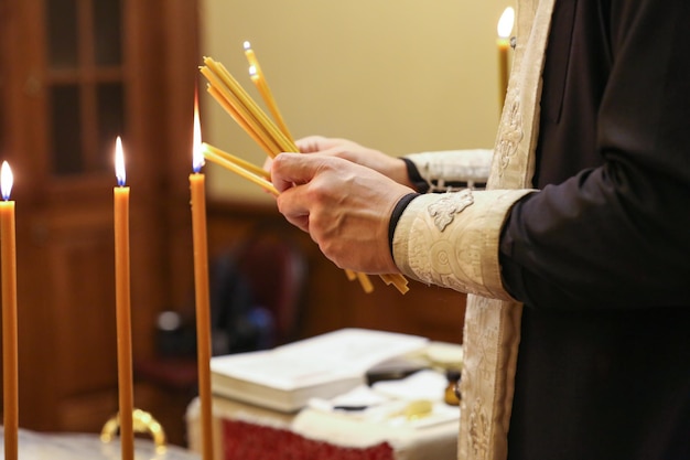 il sacerdote accende candele per il rito del battesimo