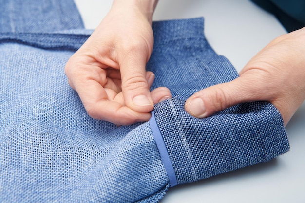 Il sarto esegue le marcature con il gesso sulla gamba dei pantaloni Cucitura dei vestiti Riparazione dei vestiti Sartoria Vista ravvicinata