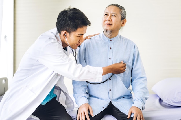 Il servizio medico dell'uomo asiatico aiuta a sostenere la discussione e la consulenza parla con il paziente asiatico anziano malato alla riunione del concetto di fiducia dell'assistenza sanitaria in ospedale e medicina