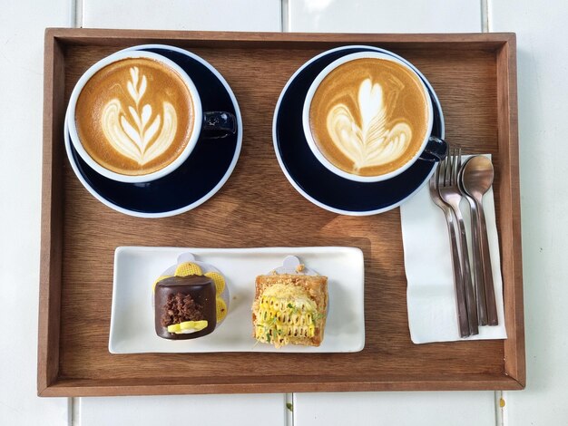 Il set per servire due tazze di caffè latte art caldo con una torta