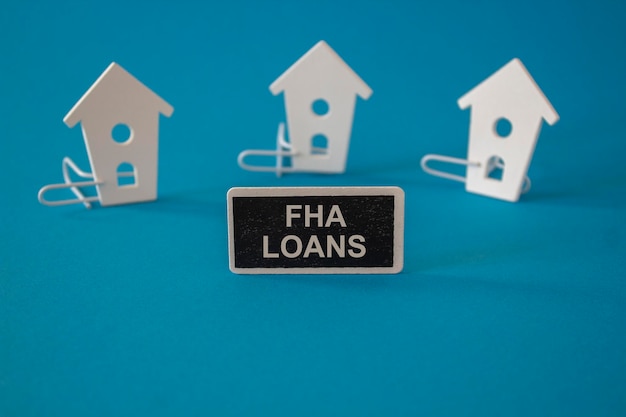 Il simbolo dei prestiti ipotecari FHA Le case in legno si trovano accanto a una lavagna di legno con la parola prestiti FHA