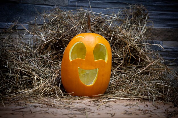 Il simbolo di Halloween della zucca gialla e sorridente felice si erge su un fieno e su un supporto di legnoJack o lantern