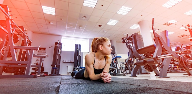 Il simpatico modello di fitness sportivo poggia sul pavimento in una moderna palestra Bella donna allenata con un corpo perfetto