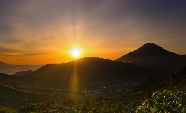 Il sole luminoso del mattino sorge da dietro tra le montagne Sindoro e Sumbing in Indonesia