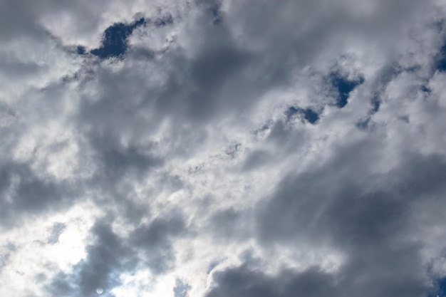 Il sole nascosto dietro nuvole bianche a mezzogiorno La luna è visibile