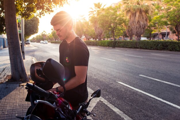 Il sole si riflette sul giovane ciclista urbano. L'uomo si prepara a guidare una moto in città.