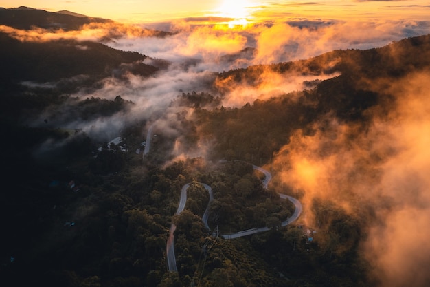 Il sole sorge nella nebbia e nelle montagne al mattino, nebbia mattutina