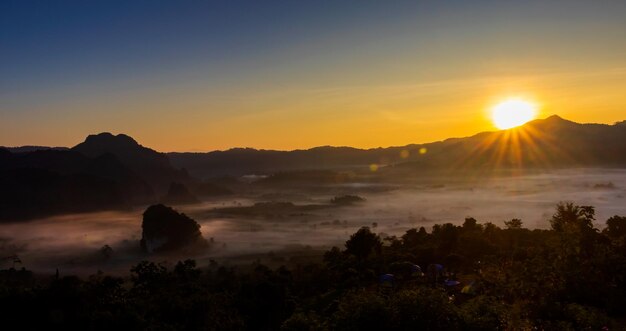 Il sole sorge sulle montagne e la nebbia