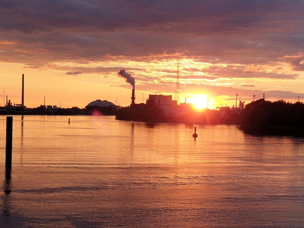 Il sole tramonta su un fiume con una centrale a carbone sullo sfondo