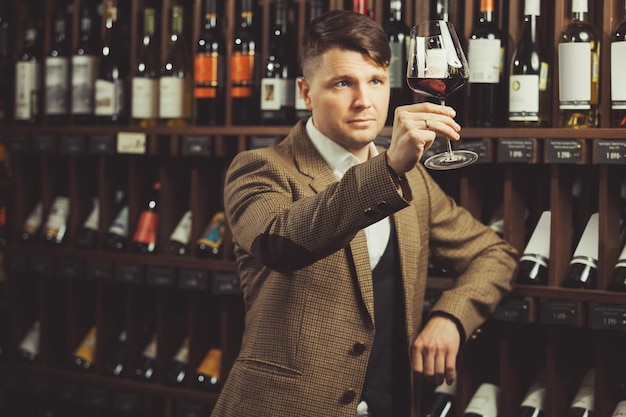 Il sommelier esamina il vino rosso in vetro in cantina