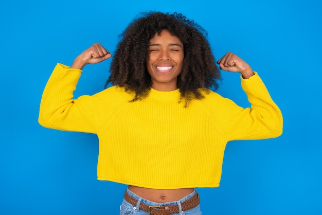 Il sorriso a trentadue denti della donna forte e potente alza le braccia e mostra i bicipiti Guarda i miei muscoli