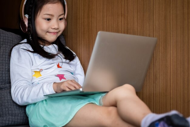 il sorriso sveglio della ragazza si siede e giocando il computer portatile nella biblioteca