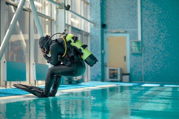 Il subacqueo maschio in attrezzatura subacquea salta in piscina