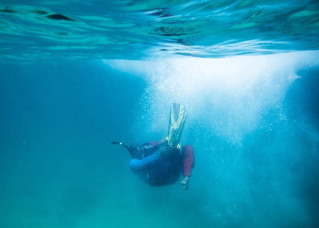 Il subacqueo si tuffa nell'oceano blu e fa brillare le bolle