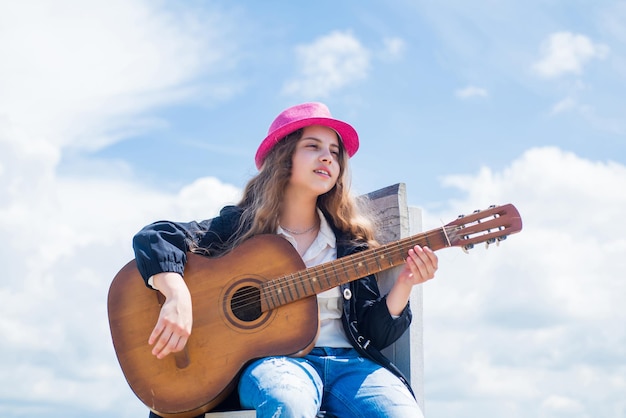 Il suo stile perfetto infanzia felice bambino carino suonare la chitarra musica all'aperto e canto scuola vocale bella ragazza adolescente con chitarra acustica kid country fashion style cantante e chitarrista