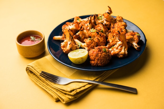Il Tandoori Gobi o cavolfiore arrosto Tikka è un piatto secco fatto tostando i cavolfiori in forno, Tandoor. È un popolare antipasto indiano. servito con ketchup. messa a fuoco selettiva