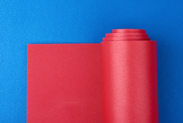 Il tappetino ritorto rosso in neoprene si trova su un tappetino blu, attrezzature sportive