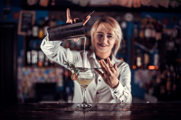 Il tapster donna sicura fa uno spettacolo creando un cocktail mentre si trova vicino al bancone del bar