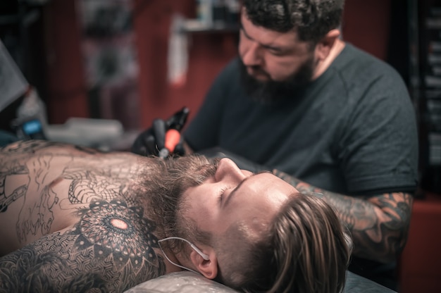 Il tatuatore fa un tatuaggio sul cliente.