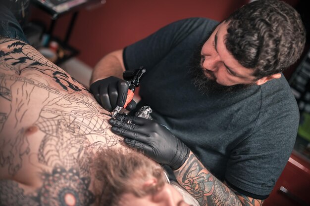 Il tatuatore mostra il processo per ottenere il tatuaggio nello studio del tatuaggio