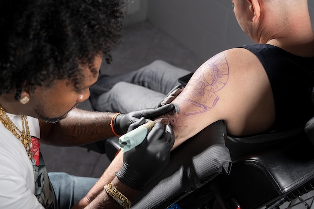 Il tatuatore professionista afroamericano fa un tatuaggio sul braccio del cliente