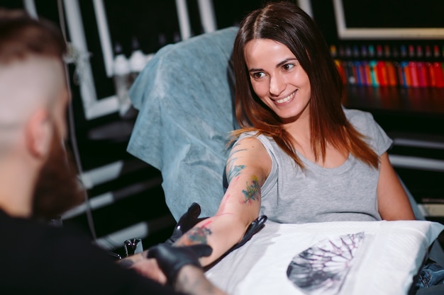 Il tatuatore professionista fa il tatuaggio su una ragazza.