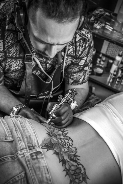 Il tatuatore professionista fa il tatuaggio sulla pelle del suo cliente