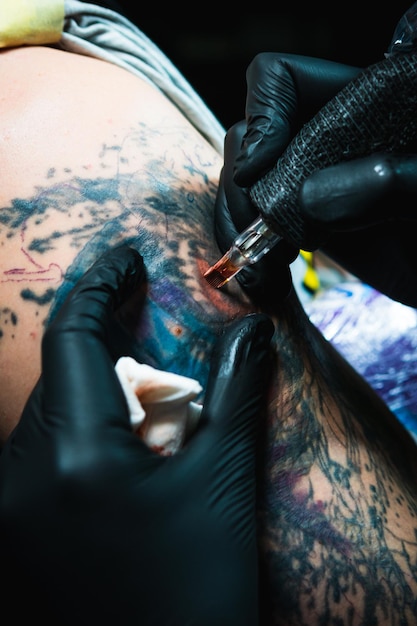 Il tatuatore professionista fa un tatuaggio su un primo piano della mano dei maschi