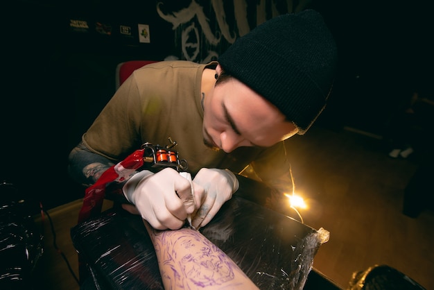 Il tatuatore professionista fa un tatuaggio sul braccio del cliente