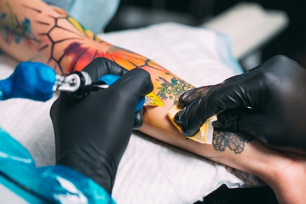 Il tatuatore professionista fa un tatuaggio sulla mano della ragazza.