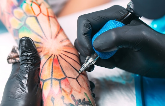 Il tatuatore professionista fa un tatuaggio sulla mano di una ragazza.