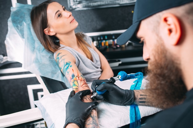 Il tatuatore professionista fa un tatuaggio sulla mano di una ragazza.