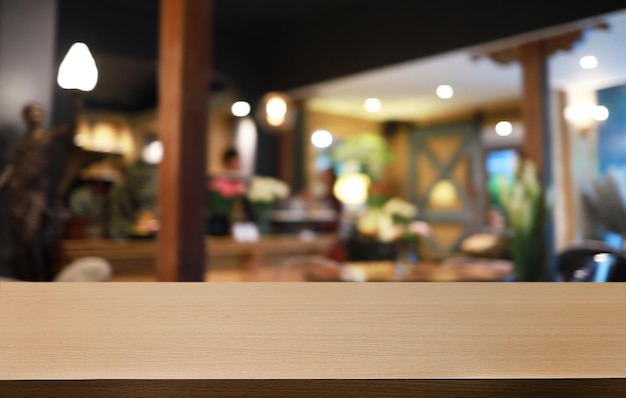 Il tavolo di legno vuoto davanti allo sfondo sfocato astratto della caffetteria può essere utilizzato per esporre o montare i tuoi prodottiMock up per l'esposizione del prodotto