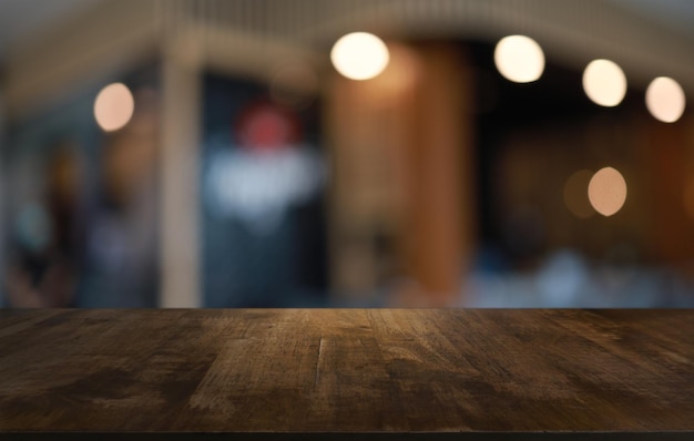 Il tavolo di legno vuoto davanti allo sfondo sfocato astratto della caffetteria può essere utilizzato per esporre o montare i tuoi prodottiMock up per l'esposizione del prodotto