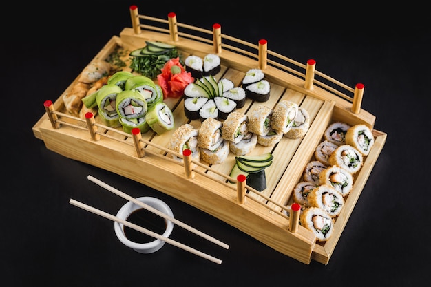 Il tavolo di sushi con la California, l&#39;avocado, il hosomaki e la tempura rotola su una tavola di legno