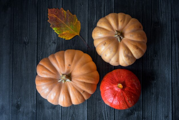 Il tavolo in legno decorato con verdure, zucche, mais e foglie autunnali. Sfondo autunnale. Giorno del Ringraziamento o concetto di Halloween.