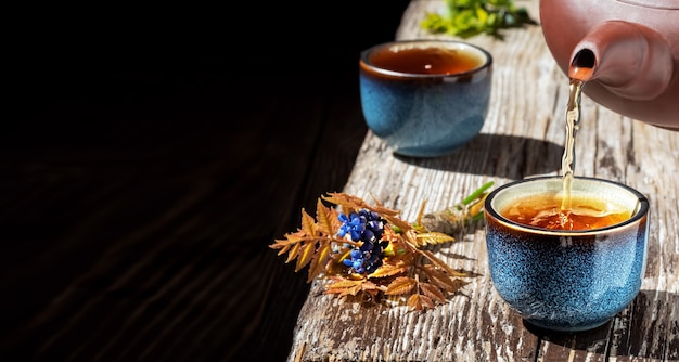 Il tè verde caldo viene versato dalla teiera nella ciotola blu
